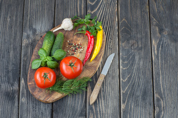 tomatoes, cucumbers, spices, herbs and knife on a wooden board