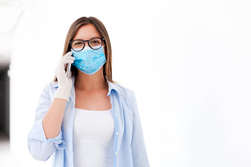 Young woman wearing mask and medical gloves. Girl talking on mobile phone. Staff in casual clothes in empty corridor indoors. Disease prevention during quarantine, health care. Lifestyle moment.