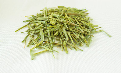 Lemon Grass (Cymbopogon citratus, Capim Limao, Santo). Pile of dried Lemongrass in white bowl. Dried sprigs of natural lemongrass, dried herb, herbal medicine. Selective focus, closeup