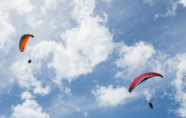 Paragliders fly in the mountains. Two paragliders against a clear blue sky.