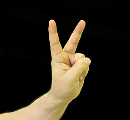 A gesture is a symbol of victory or luck or success. Two fingers in the shape of the letter V. Black background