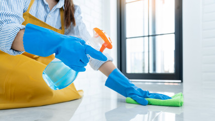 Housekeeper maid wearing rubber gloves with cloth cleaning or applying floor care and cleaners at home, housework and housekeeping concept.
