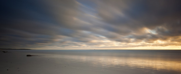 long exposure image of sandy beach and clouds