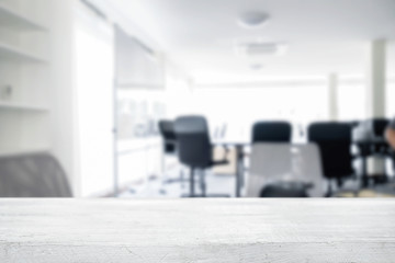 Empty wooden desk space over blurred office or meeting room background. Product display.
