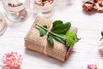 Bar of homemade soap wrapped in hemp fabric on wood background