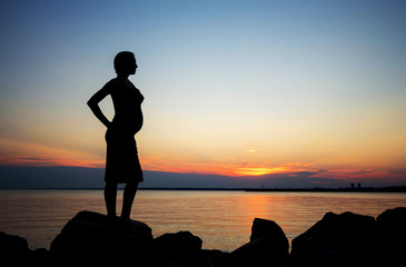 Silhouette of a  beautiful young pregnant woman on a background of the sea.