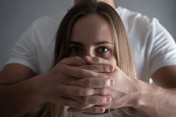 Victim of domestic violence. Violence against women,Scared woman with man's hand covering her mouth