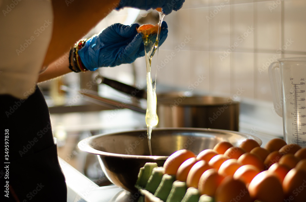 Wall mural blurry chef hands crackin eggs on professional stainless steel kitchen table