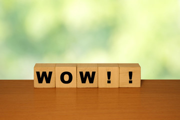 WOW message word on a wooden desk on cube blocks with a green nature background.