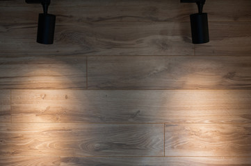Two lamps shine on a wooden wall.