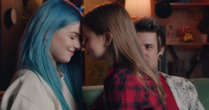 Young modern familly smiling and having fun at sofa in living room.Modern millennial mom and her pretty daughter rubbing noses and giving kiss while enjoing time together at home.