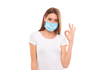 European girl in a medical mask, shows ok. Conceptual photo on the theme of the Covid 2019 pandemic.