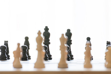 Black pieces of the chessboard and in the foreground white pieces blurred