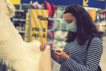 Woman in medical mask choosing goods in a store. Concept of shopping during quarantine at covid-19...