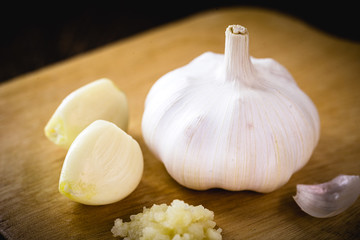 Brazilian garlic cloves and bulb on vintage wooden board, sliced, closed and chopped garlic. Spicy seasoning.