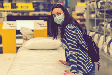 Woman in medical mask choosing goods in a store. Concept of shopping during quarantine at covid-19...