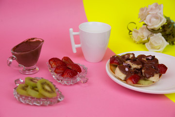 Fresh fruit dessert poured with chocolate. pink background