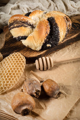 Bun with poppy seeds and honey on a wooden board. Shallow depth of field.