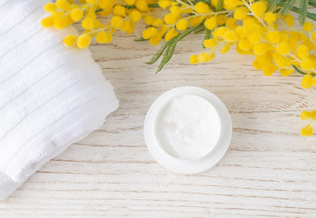 Beauty and fashion concept with spa set on white and blue rustic wooden background. Cream, towel and yellow flowers. top view