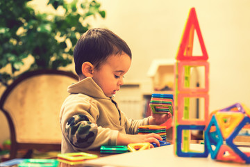 The boy 2 years building a tower from a bright constructor. little smiling boy playing with...