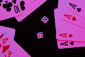 Playing cards with dice in neon blue-pink light on a black background. Game addiction. Poker