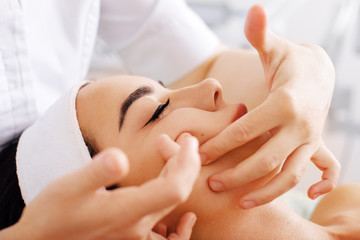Fototapeta na wymiar Beautiful woman having spa facial massage in beauty salon