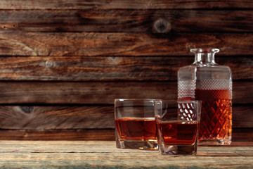Glasses and decanter of whiskey on a old wooden table.