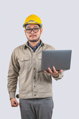 Young computer engineer asian man with laptop and yellow hard hat