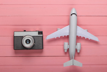 Air Tourism or travel flat lay. Airplane figurine with camera on a pink wooden background. Top view