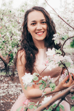 Beautiful portrait of a young woman in flowers. Photo of a brunette with flowers. Photoshoot with an apple tree.