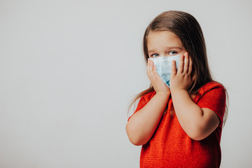 Little european girl wearing mask for protect pm2.5 and Covid-19. Sick child Little girls look at the camera posing in the studio in a red dress with a medical mask on her face. Copy space.   