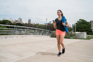 Athletic woman holding a training mat.