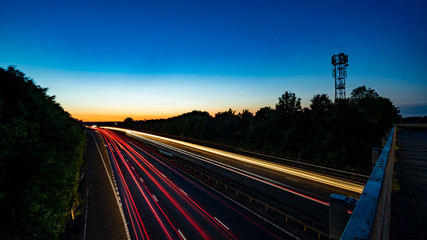 Side angle long exposure shot of motorway with cell tower silhouette