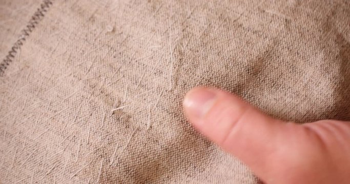 Hands of caucasian man : white threads, the needle on the background of linen fabric. the concept of embroidery and needlework. Copy space. Free space for text.