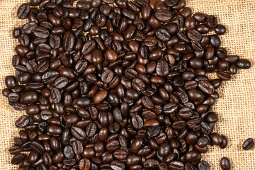 Coffee beans on brown linen fabric background.Roasted coffee beans texture, used as a background.Flat lay, top view, copy space.