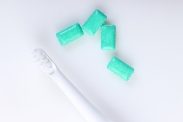 Toothbrush with chewing gum on white background. Caring for dental health, fresh breath. Top view