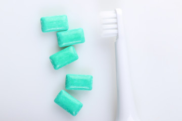 Toothbrush with chewing gum on white background. Caring for dental health, fresh breath. Top view