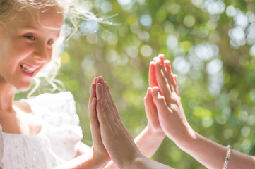 Two young girl friends sitting outdoors playing patty cake, Summertime fun