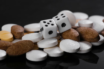 Fototapeta na wymiar Dice and pills on black background. Game Addiction Treatment