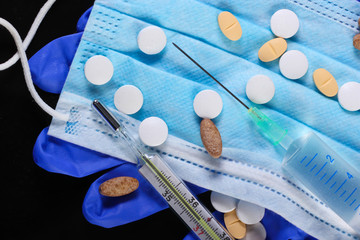 Medical still life. Syringe, thermometer, medical mask with gloves, pills. Diagnosis, protection and treatment of covid-19. Global pandemic
