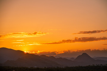 The sun setting behind mountainsThe sun setting behind mountains in the Sonoran Desert of Arizona. in the Sonoran Desert