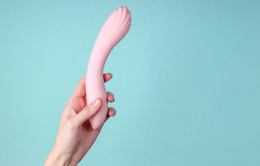 hand holding Sex toy for women on blue background.