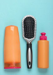 Shampoo bottles, hair conditioner, hair brushes on blue background. Hair care. Hygiene. Beauty flat lay
