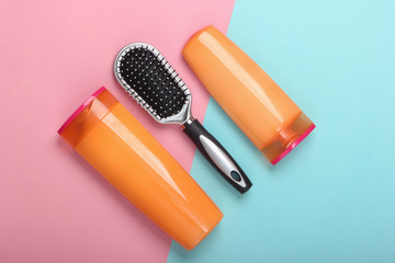 Shampoo bottles, hair conditioner, hair brushes on blue pink background. Hair care. Hygiene. Beauty flat lay
