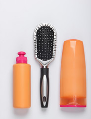 Shampoo bottles, hair conditioner, hair brushes on white background. Hair care. Hygiene. Beauty flat lay