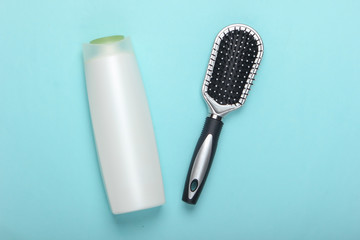Hair brush with shampoo bottle on blue pastel background. Hair care. Hygiene. Beauty flat lay. Top view