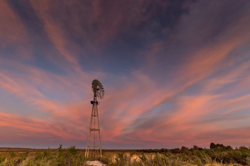 landscape image in the karoo, South Africa with windmill at sunset