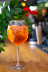 Aperol is an alcoholic cocktail. Orange. Cold drink with ice cubes. The glass is on the bar. Green in the background. The background is blurred. Menu for restaurants, cafes and bars.