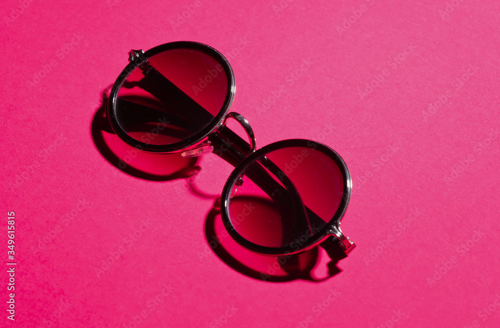 Wall mural stylish fashionable round sunglasses on pink paper background. minimalism