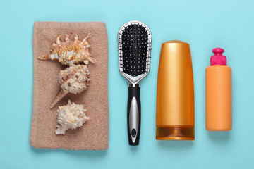 Fototapeta na wymiar Bath beauty products. Bottle of shampoo, cockleshells, towel, hairbrush on a blue background. Top view. Flat lay